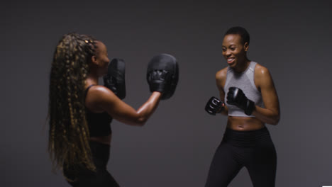 Studio-Shot-Of-Woman-Wearing-Boxing-Gloves-Sparring-With-Trainer-2